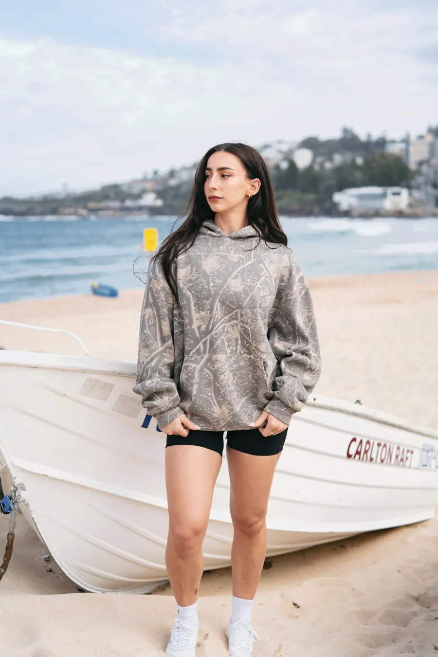 Woman in a Deadwood Camo Heavyweight hoodie by a boat