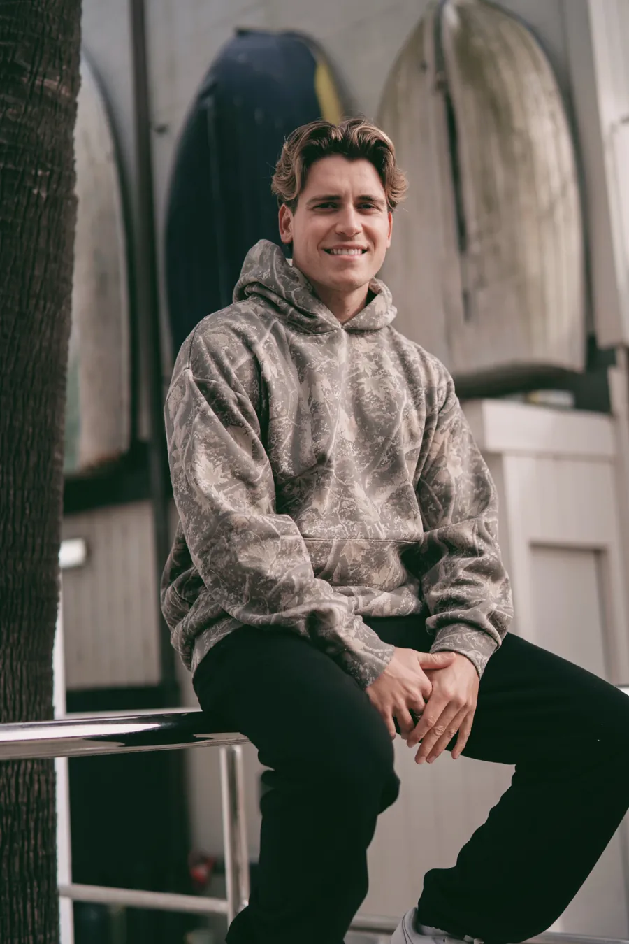 Man in a Deadwood Camo Heavyweight hoodie, seated